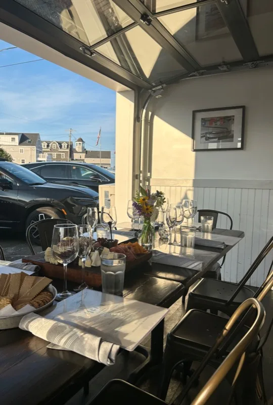 Open-air dining table with roll-up garage door open to ocean breeze